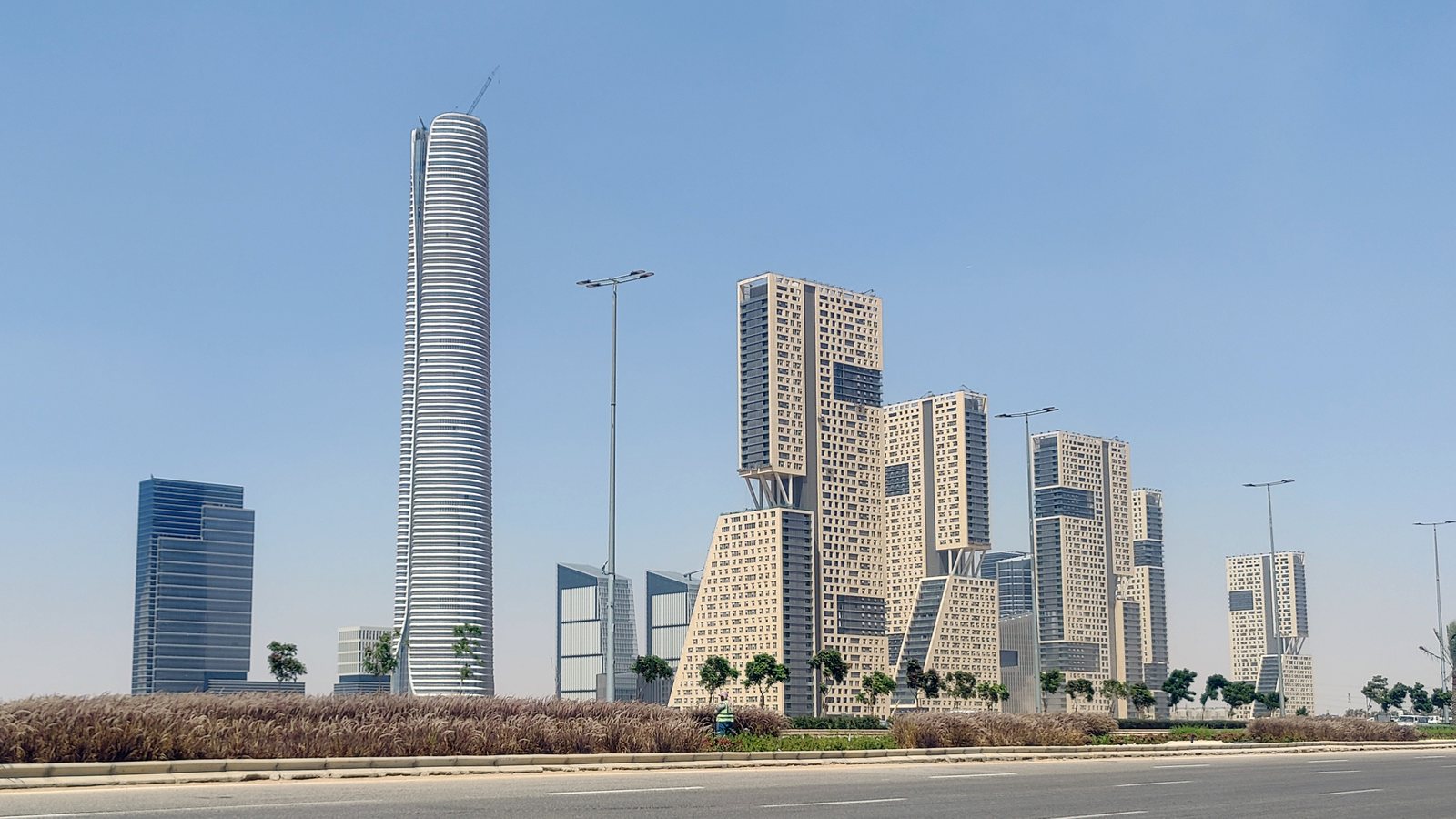 Wide street-level view of the New Administrative Capital's Central Business District, with the Iconic Tower rising above the cluster of CBD towers.