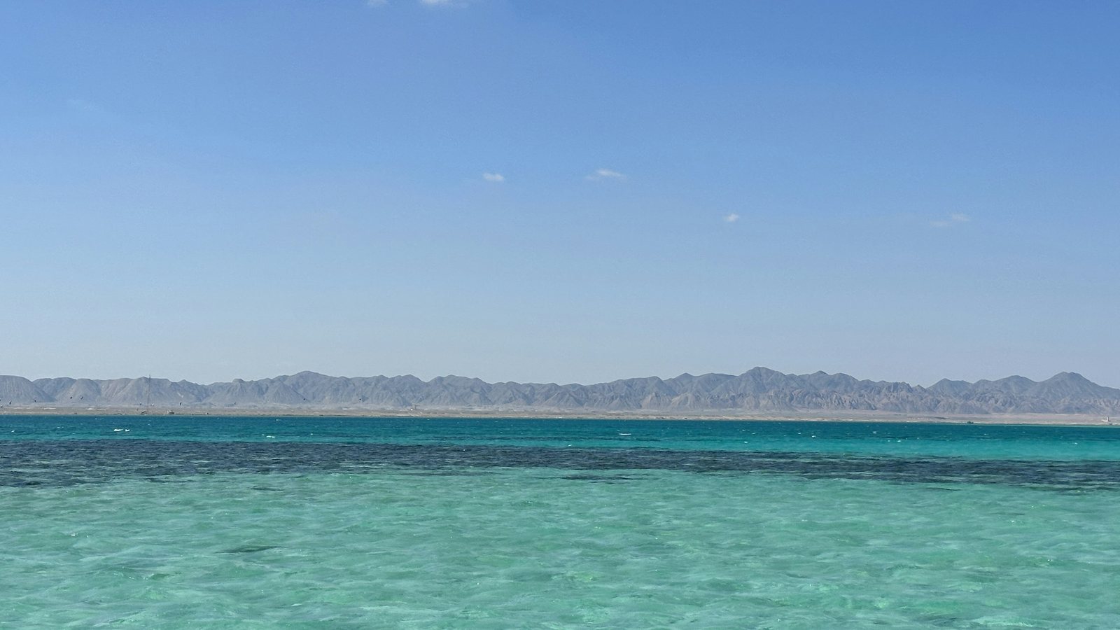 Brilliant turquoise-to-deep-blue Red Sea water meeting the bare Red Sea mountain range on the horizon near El Gouna.
