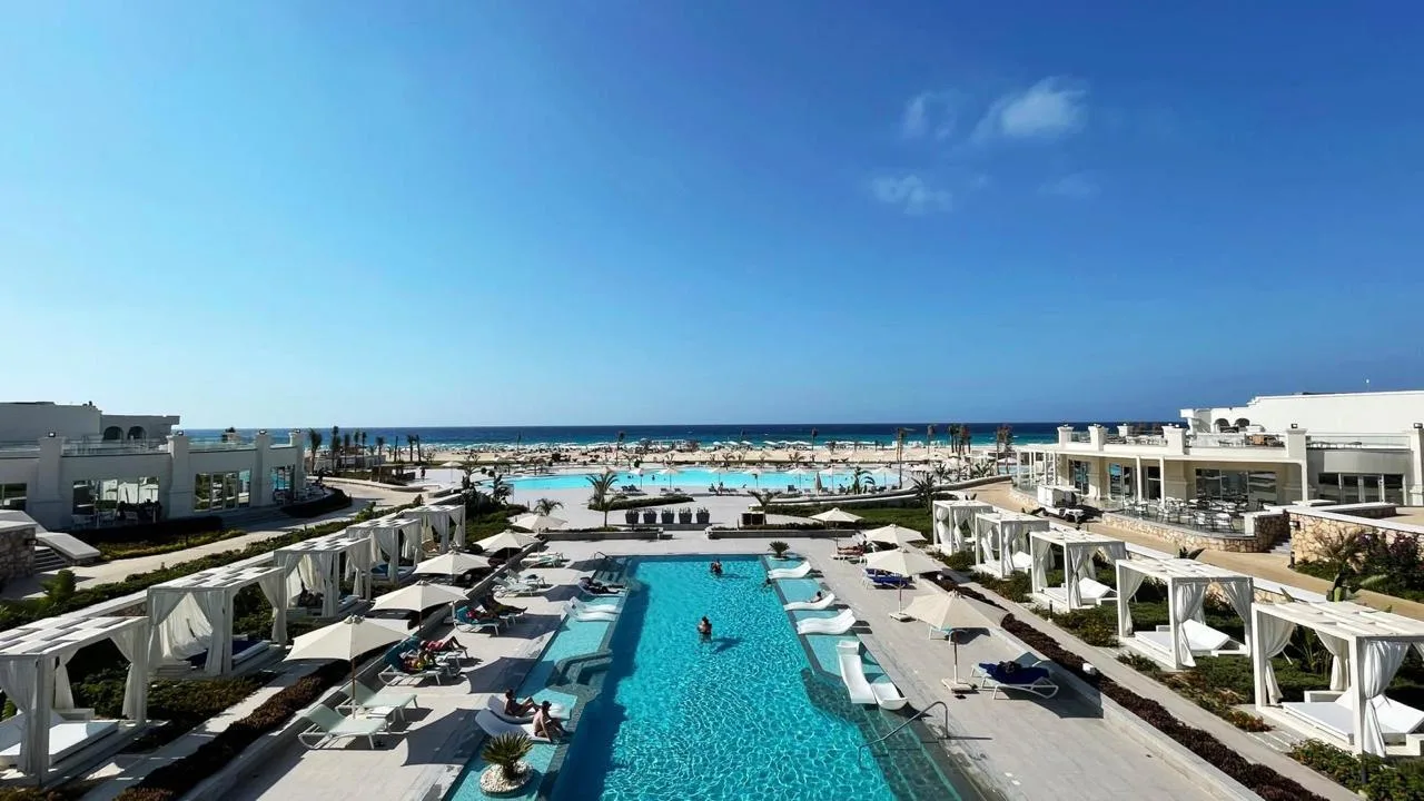 Hacienda Heneish beach-club pool and Mediterranean shoreline in a developer-supplied August 2026 photograph